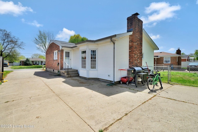 exterior space featuring a chimney, brick siding, and fence