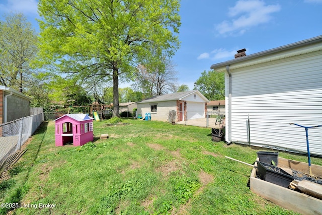 view of yard with a detached garage, a fenced backyard, and an outbuilding