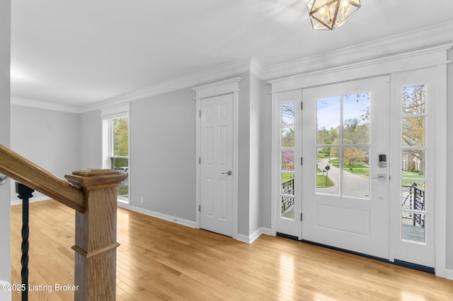 foyer with stairs, light wood finished floors, baseboards, and ornamental molding
