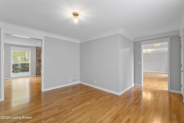 empty room featuring light wood-type flooring, baseboards, visible vents, and crown molding