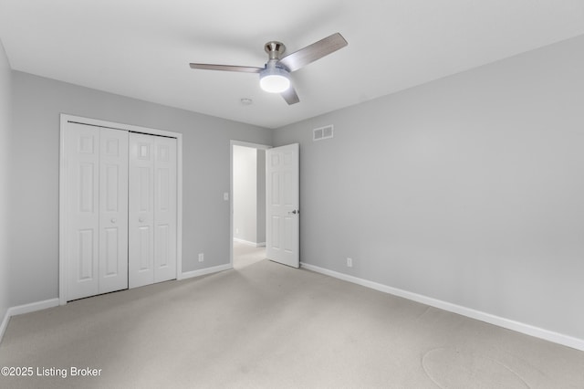 unfurnished bedroom with visible vents, a closet, baseboards, light colored carpet, and ceiling fan
