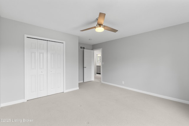 unfurnished bedroom featuring visible vents, light carpet, a closet, baseboards, and ceiling fan