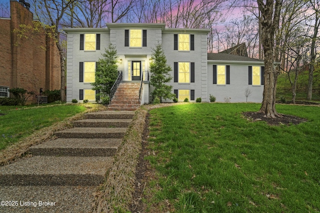 colonial-style house with brick siding and a yard