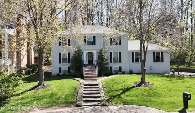 colonial house with a front lawn, stairs, and stucco siding
