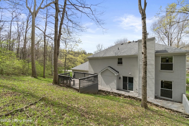 back of property with roof with shingles, a deck, a chimney, and brick siding