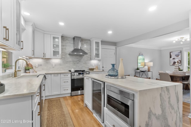 1907 Charbdin Pl, Louisville, KY 40207 - kitchen featuring stainless steel appliances, wall chimney exhaust hood, a sink, light wood-style floors, and a center island