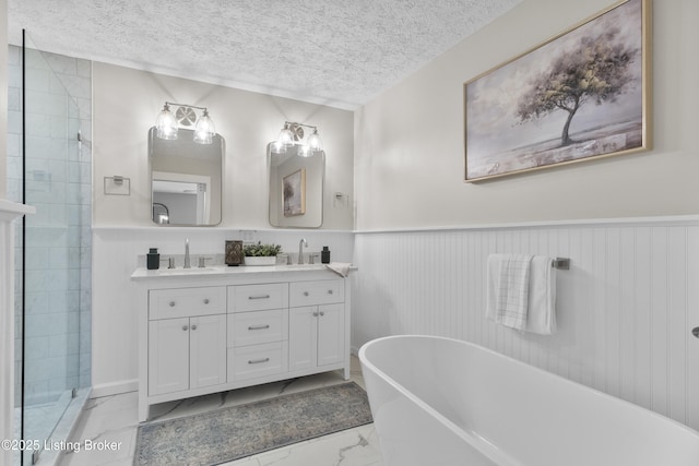 1907 Charbdin Pl, Louisville, KY 40207 - bathroom with marble look tiles, a freestanding bath, a wainscoted wall, double vanity, and a textured ceiling