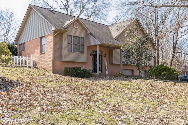 view of front of house with a garage, fence, roof with shingles, and brick siding