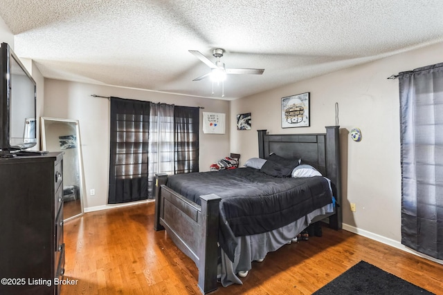 bedroom featuring a textured ceiling, a ceiling fan, wood finished floors, and baseboards