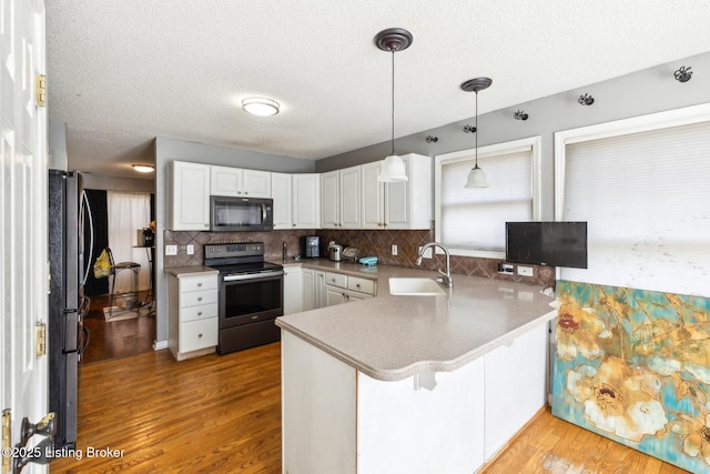 kitchen with electric range, white cabinetry, a peninsula, and a sink