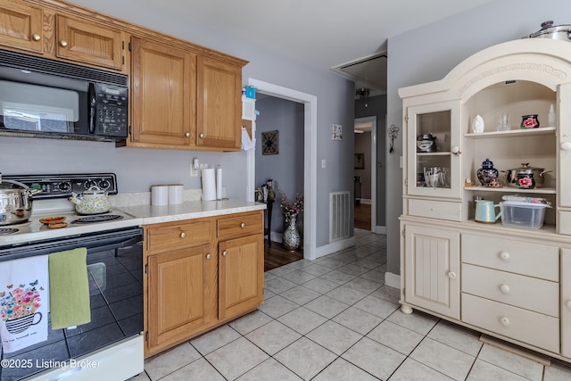 kitchen with light countertops, black microwave, visible vents, white electric range, and light tile patterned flooring