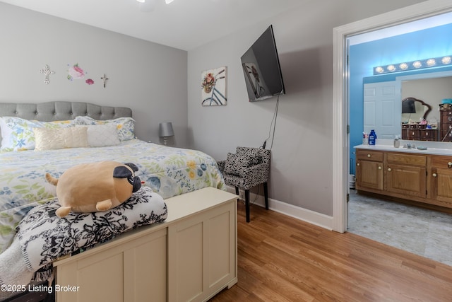 bedroom with light wood-style floors, ensuite bathroom, and baseboards