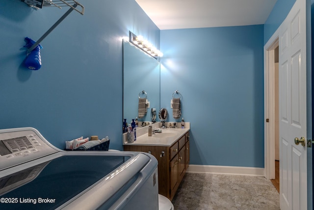 bathroom with vanity, washer / clothes dryer, and baseboards