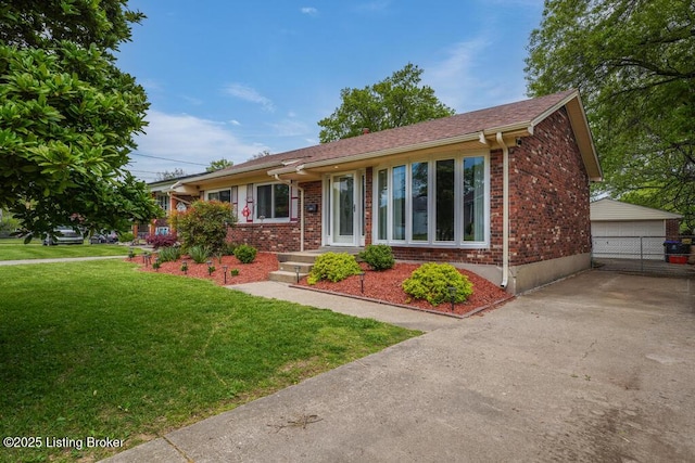 single story home with a detached garage, brick siding, an outdoor structure, and a front lawn