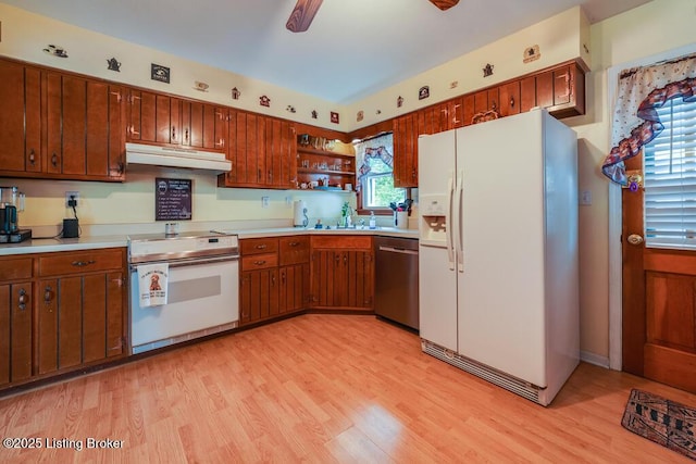 kitchen with light countertops, light wood finished floors, under cabinet range hood, and white appliances