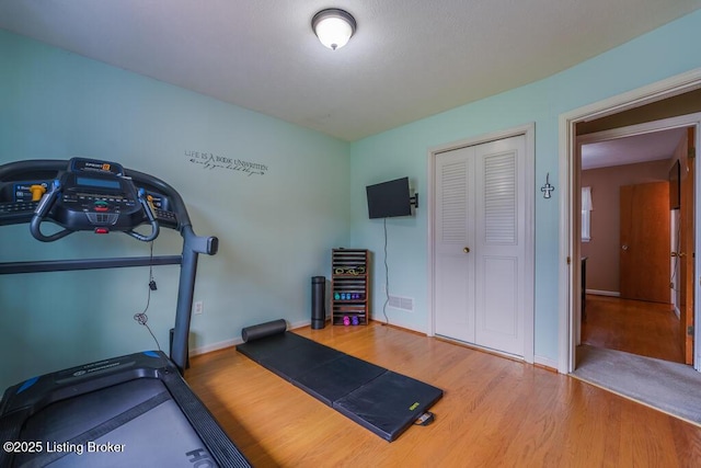 workout area with baseboards and wood finished floors
