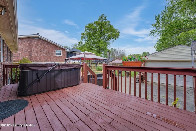 wooden terrace with a garage and a hot tub