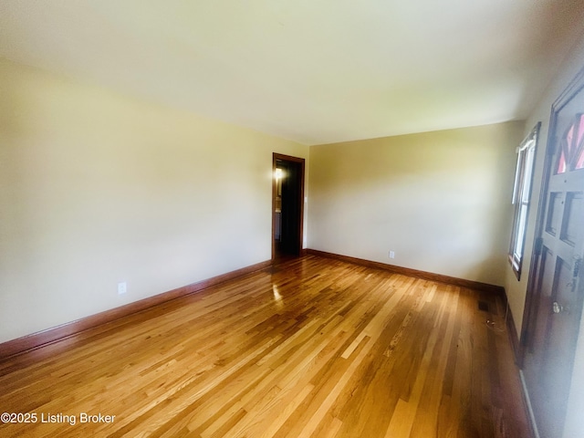 spare room featuring light wood-style flooring and baseboards