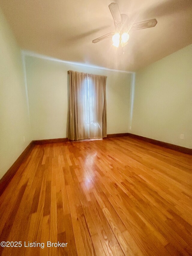 empty room featuring light wood-type flooring, a ceiling fan, and baseboards