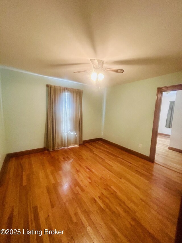 empty room featuring a ceiling fan, baseboards, and light wood-type flooring