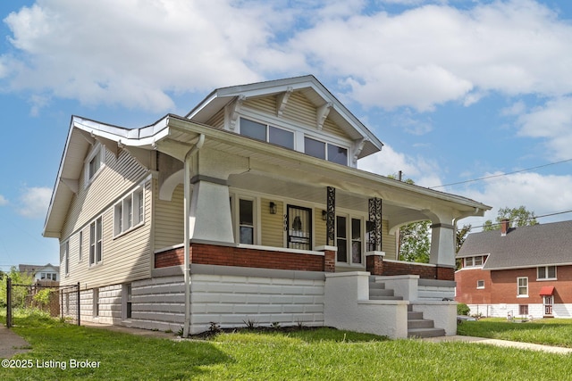 bungalow featuring covered porch, a front yard, and brick siding