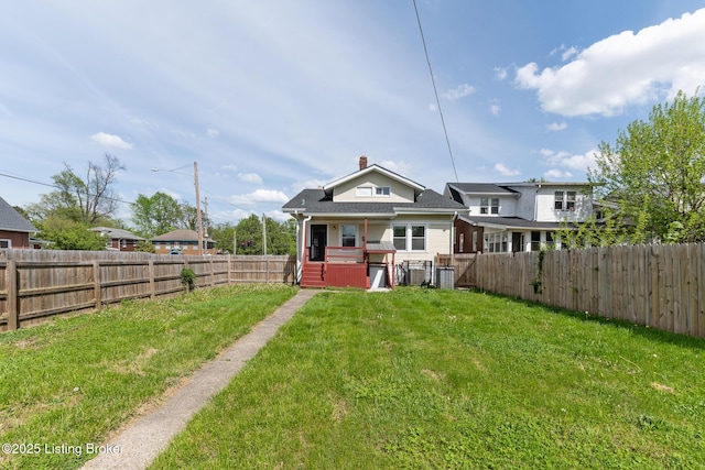 rear view of house with cooling unit, a yard, and a fenced backyard