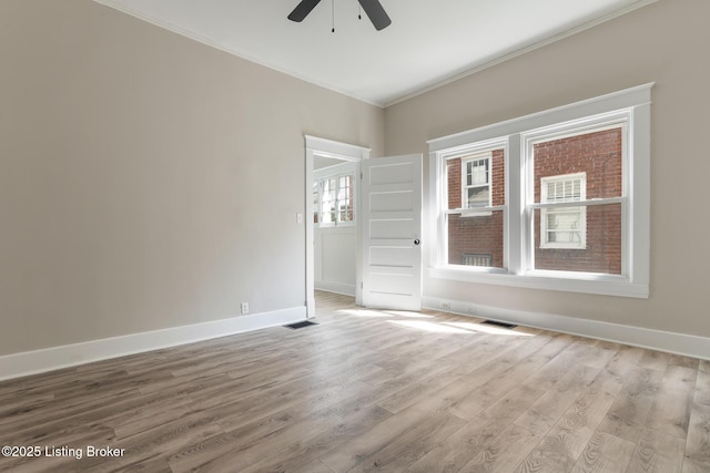 spare room with ornamental molding, ceiling fan, wood finished floors, and baseboards