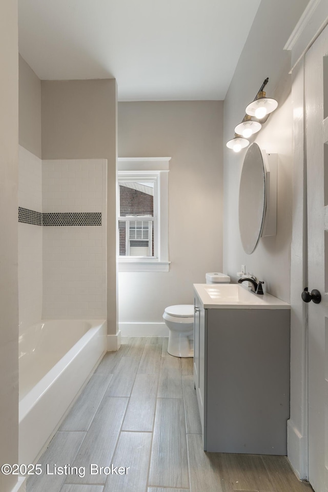 full bath with baseboards, wood finished floors, toilet, and vanity