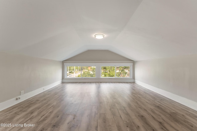 additional living space with wood finished floors, vaulted ceiling, and baseboards