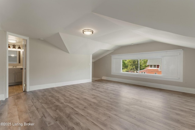 additional living space with baseboards, wood finished floors, and lofted ceiling