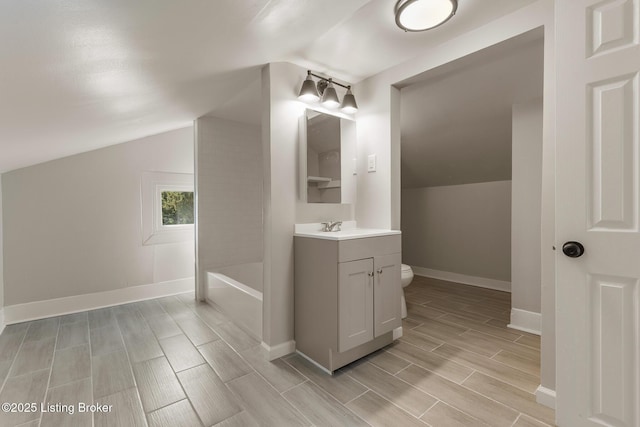 full bathroom with vanity, toilet, vaulted ceiling, baseboards, and wood finish floors