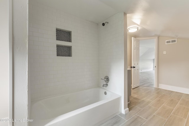 bathroom with lofted ceiling, visible vents,  shower combination, and baseboards