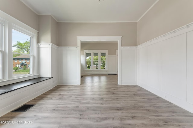 interior space featuring visible vents, a healthy amount of sunlight, ornamental molding, and light wood-style floors