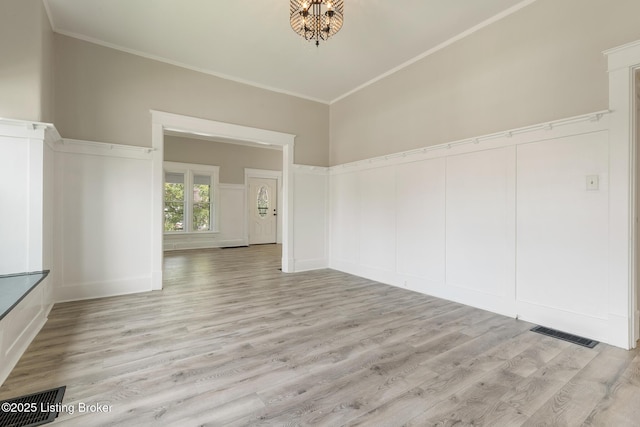 empty room featuring crown molding, visible vents, and light wood-style flooring