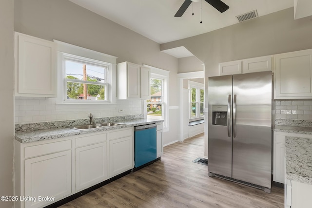 kitchen featuring a sink, stainless steel fridge, ceiling fan, dishwashing machine, and backsplash