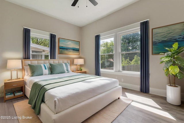 bedroom featuring baseboards, wood finished floors, and a ceiling fan