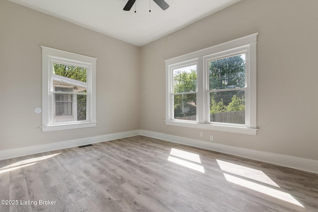 spare room featuring wood finished floors, ceiling fan, visible vents, and baseboards