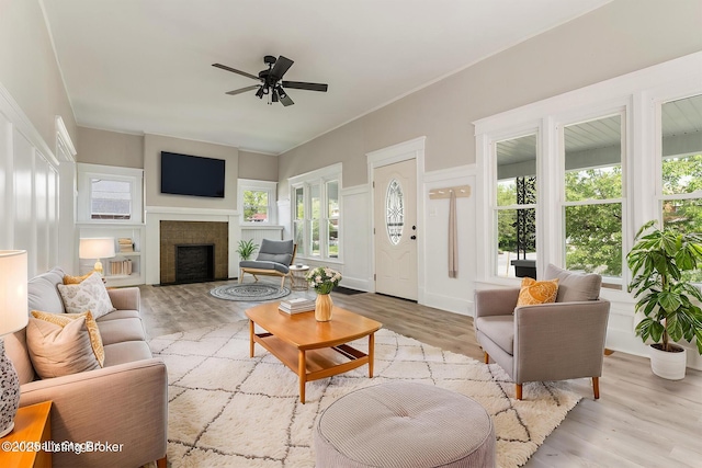 living room with light wood-style flooring, ceiling fan, and a fireplace