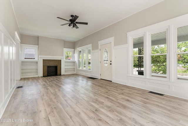 unfurnished living room featuring wood finished floors, visible vents, a healthy amount of sunlight, and a ceiling fan