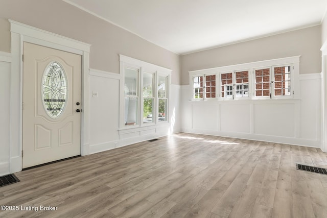 entryway featuring visible vents, light wood-style floors, and a decorative wall