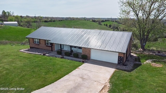 view of front of house with brick siding, metal roof, a front yard, and a garage
