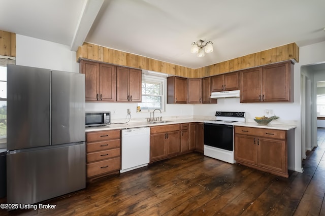 kitchen with dark wood-style floors, light countertops, under cabinet range hood, a sink, and appliances with stainless steel finishes