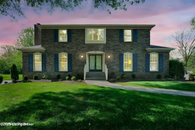 view of front of home featuring a front yard, entry steps, and brick siding