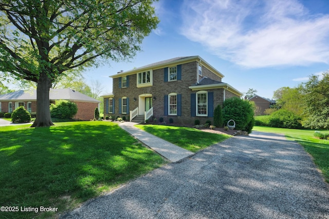 colonial-style house featuring a front yard, entry steps, and brick siding