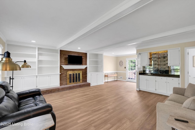 living room featuring ornamental molding, light wood-style floors, a fireplace, and built in features