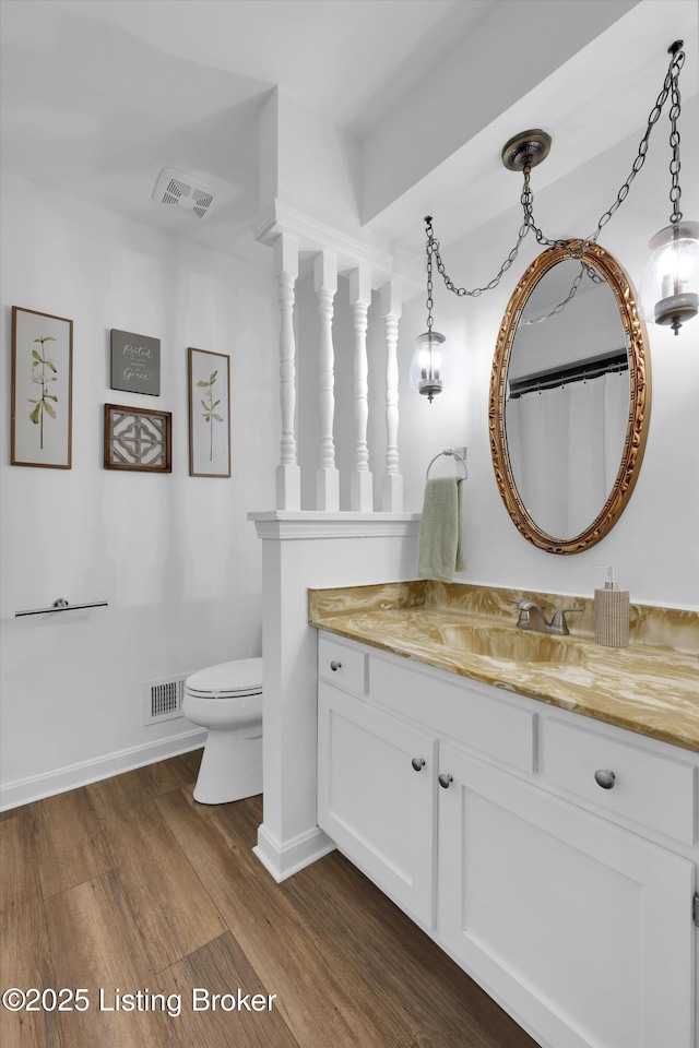 full bath with wood finished floors, toilet, vanity, baseboards, and visible vents
