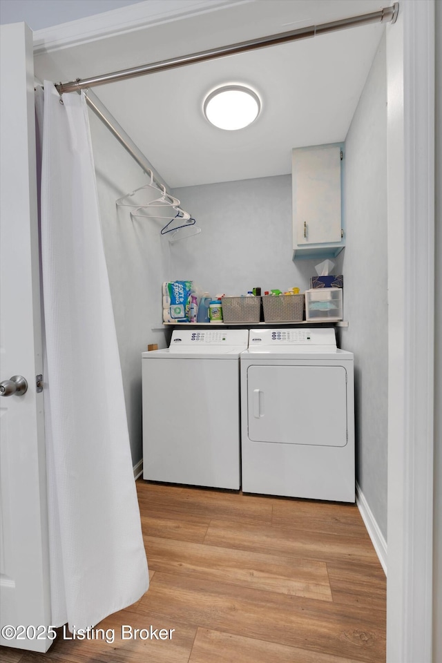 washroom with light wood finished floors, cabinet space, and washing machine and clothes dryer