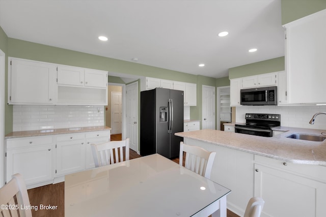 kitchen featuring stainless steel microwave, tasteful backsplash, black electric range oven, a sink, and fridge with ice dispenser