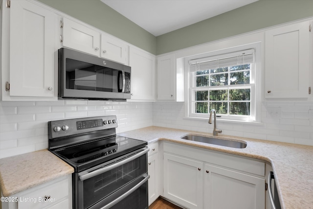 kitchen featuring white cabinetry, stainless steel appliances, light countertops, and a sink