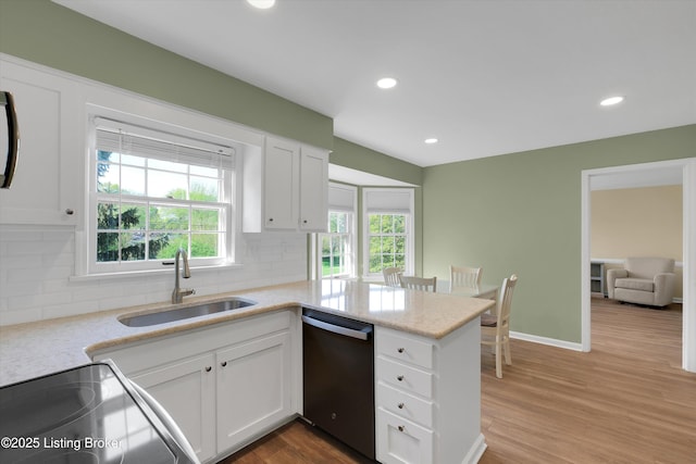 kitchen with dishwashing machine, decorative backsplash, white cabinets, and a sink